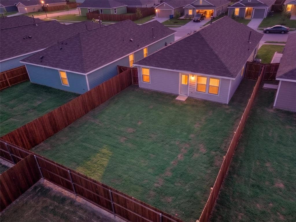 6005 Determine Lane, Forney, TX 75126 Spacious backyard featuring a full privacy fence, manicured lawn, and a light-colored exterior with multiple windows