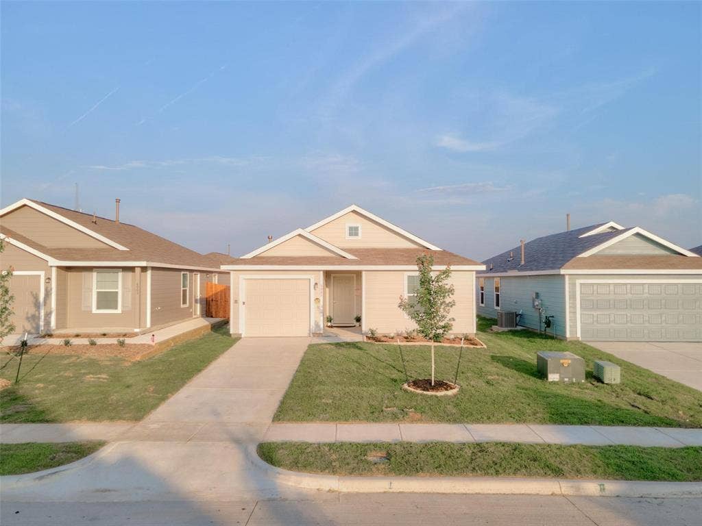 6005 Determine Lane, Forney, TX 75126 Contemporary single-story residence featuring a front-facing garage, a concrete driveway, and a manicured lawn