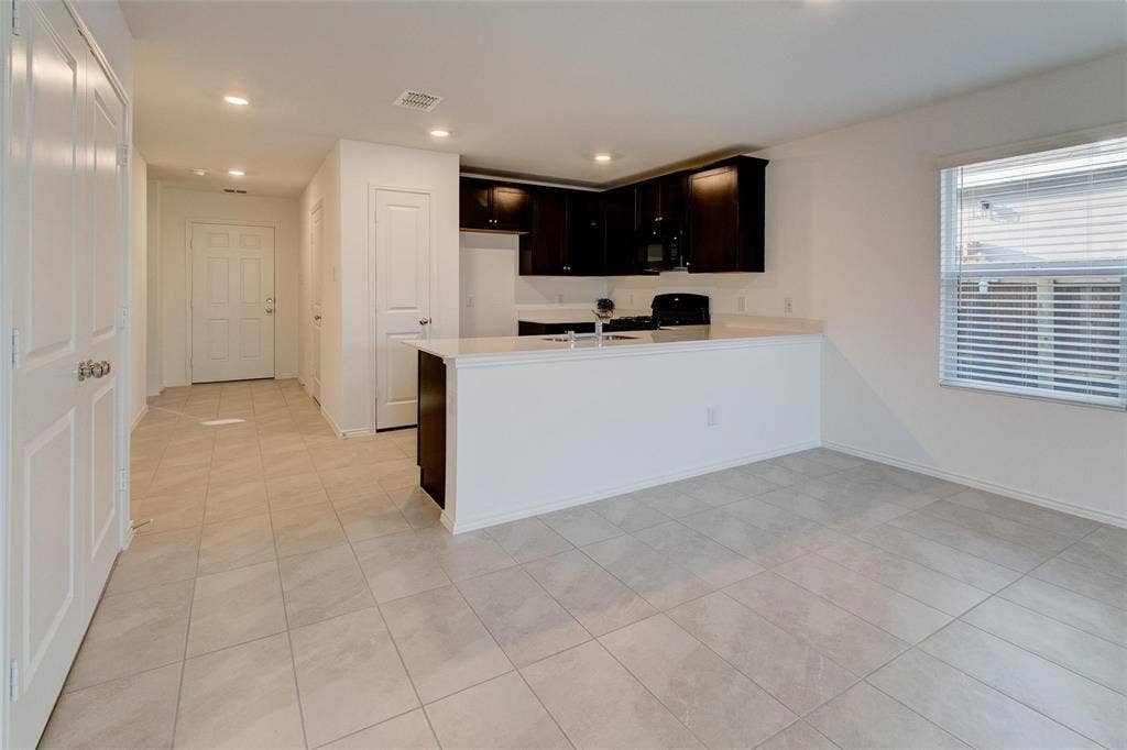 6005 Determine Lane, Forney, TX 75126 Open-concept layout featuring light-toned tile flooring, recessed lighting, and a kitchen with dark wood cabinetry
