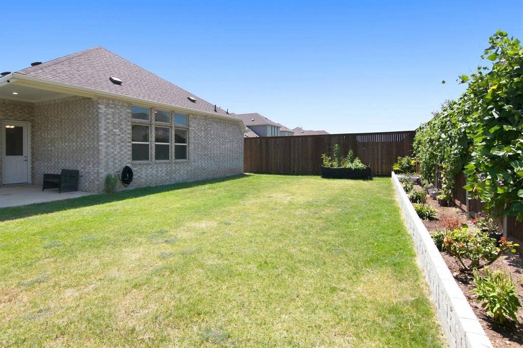 944 Tara Court, Haslet, TX 76052 Expansive green lawn with a covered patio area, featuring a brick exterior and a privacy fence