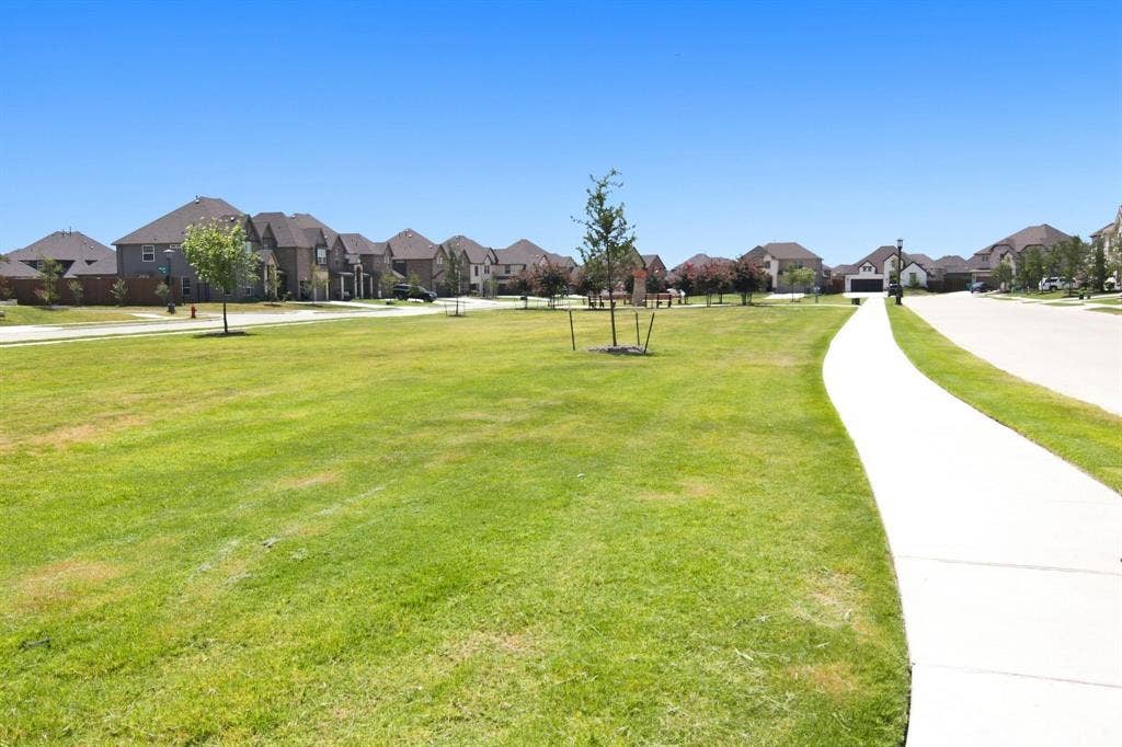 944 Tara Court, Haslet, TX 76052 Expansive green space featuring a paved walking path, scattered young trees, and a backdrop of residential homes