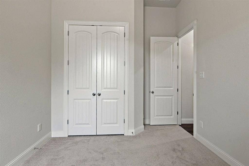 944 Tara Court, Haslet, TX 76052 Room featuring a pair of white paneled bifold doors with chrome hardware, light gray carpeting, and white baseboards