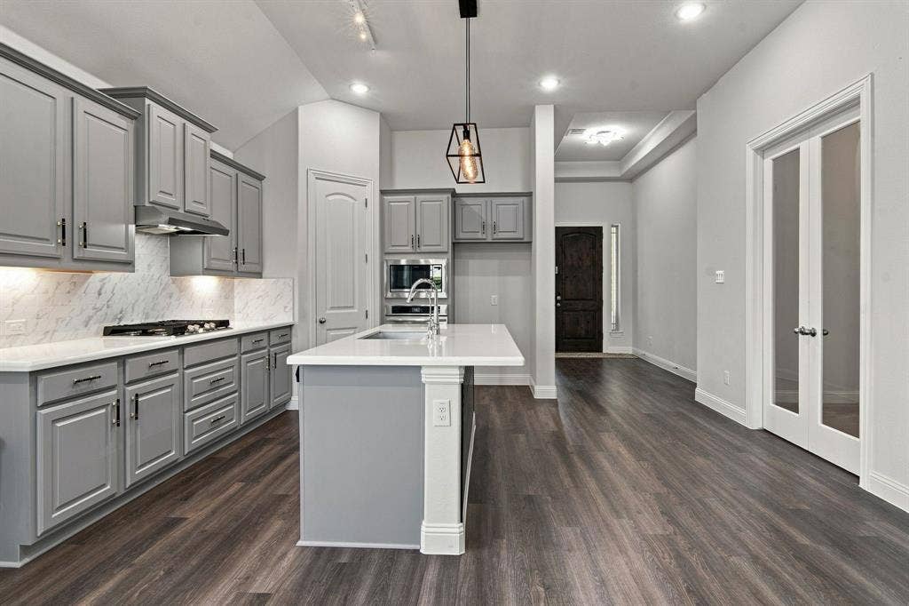 944 Tara Court, Haslet, TX 76052 Open-concept kitchen featuring an island with a white countertop, gray cabinetry with dark hardware, a gas cooktop, and wood-finish flooring