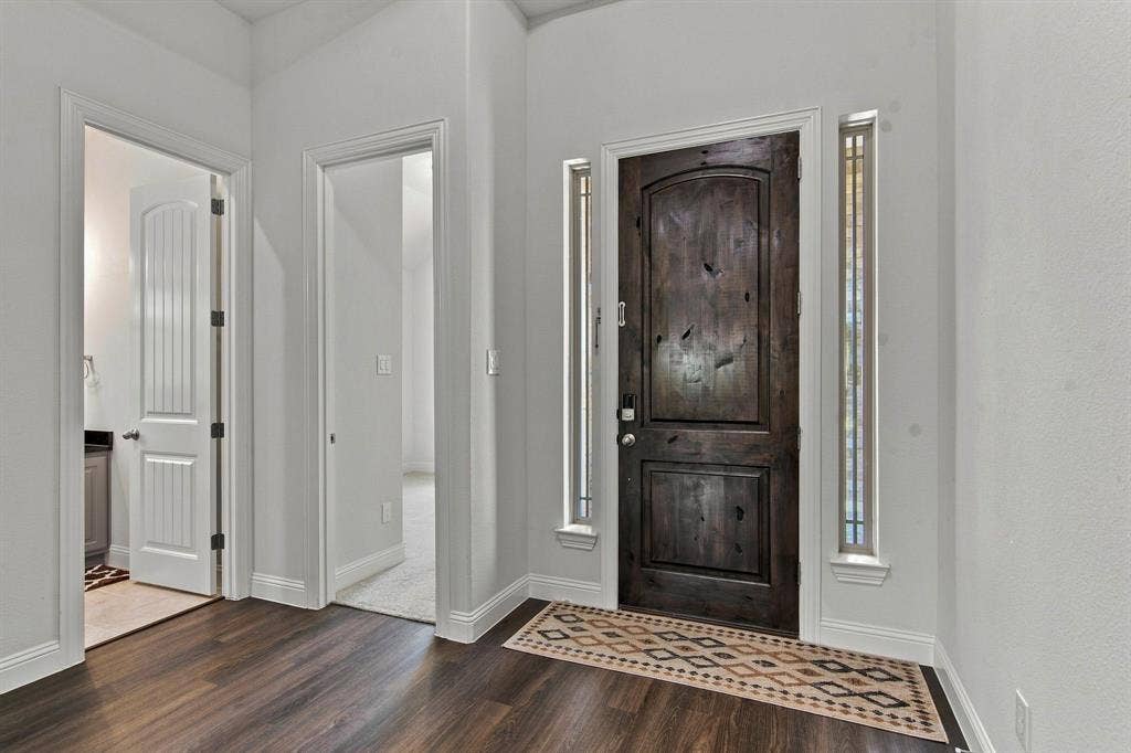 944 Tara Court, Haslet, TX 76052 Rich wood-finish flooring complements the dark wood front door, flanked by two narrow sidelight windows