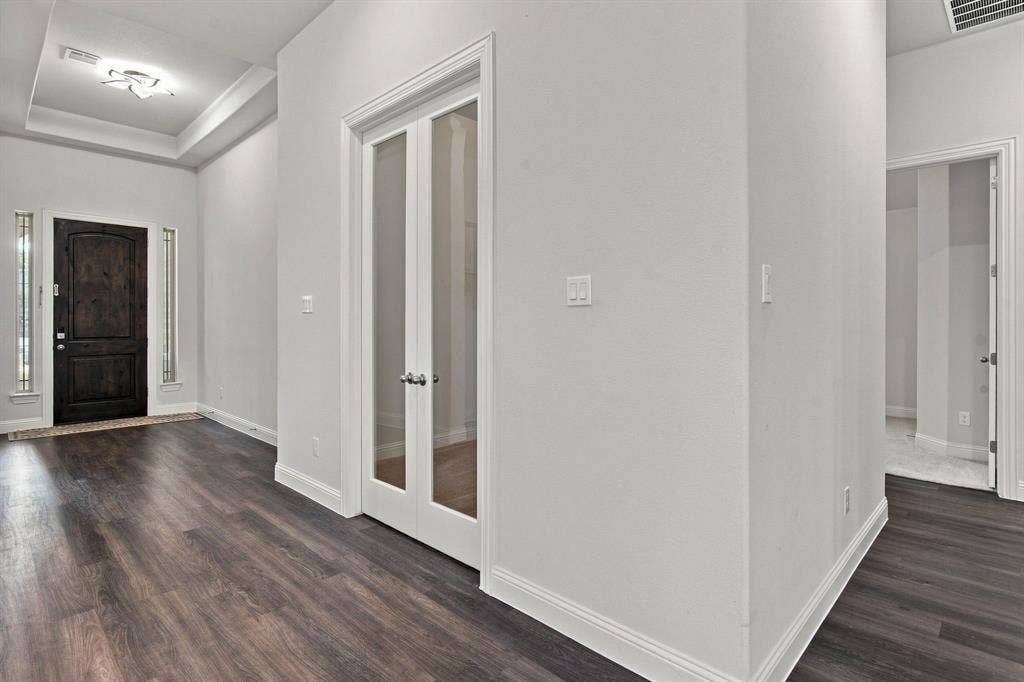 944 Tara Court, Haslet, TX 76052 Entryway featuring wood-finish flooring, a dark wood front door with sidelight windows, a tray ceiling with an attached light fixture, and white double French doors with frosted glass panels