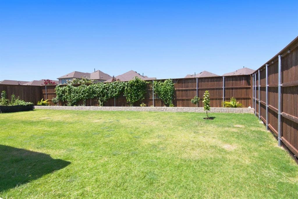 944 Tara Court, Haslet, TX 76052 Expansive backyard featuring a manicured lawn bordered by sturdy metal fencing and mature climbing vines