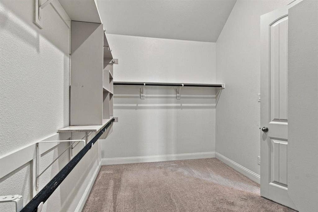 944 Tara Court, Haslet, TX 76052 Walk-in closet featuring built-in shelving, multiple hanging rods, and neutral-toned carpeting