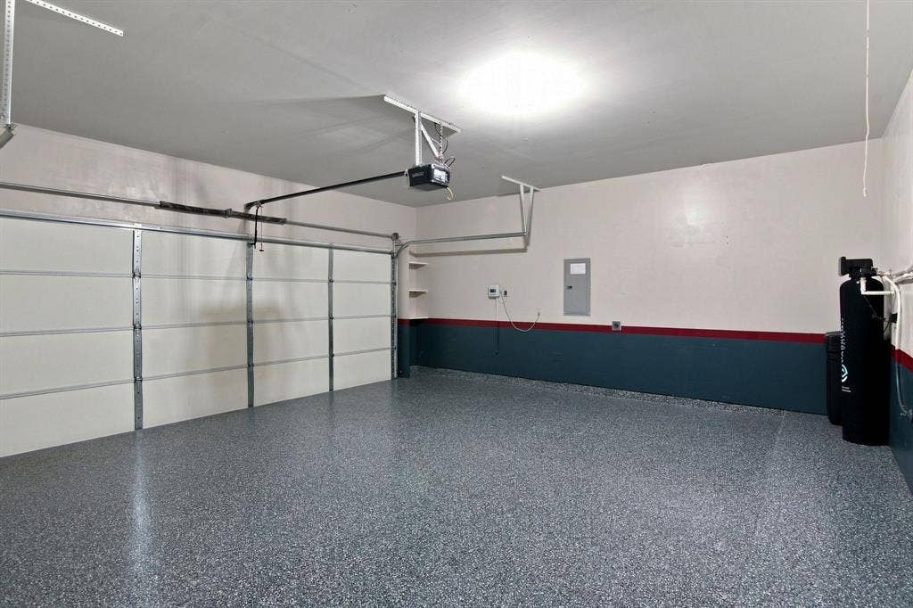 944 Tara Court, Haslet, TX 76052 Spacious garage featuring a finished epoxy floor, white paneled overhead door, automatic opener, and overhead lighting