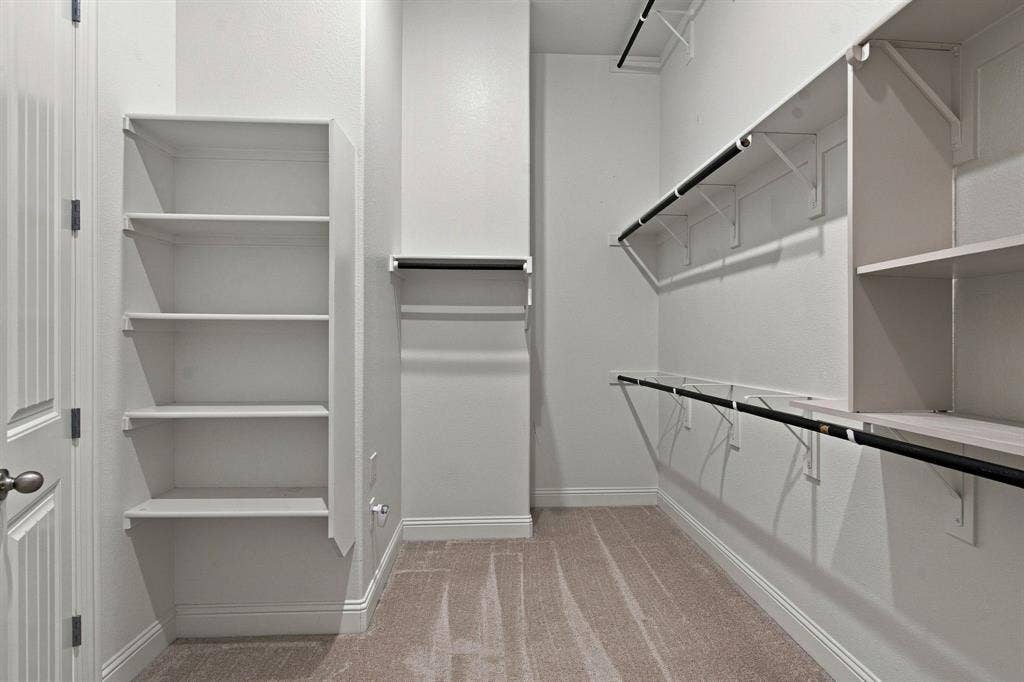 944 Tara Court, Haslet, TX 76052 Walk-in closet featuring built-in shelving, multiple hanging rods, and neutral-toned carpeting