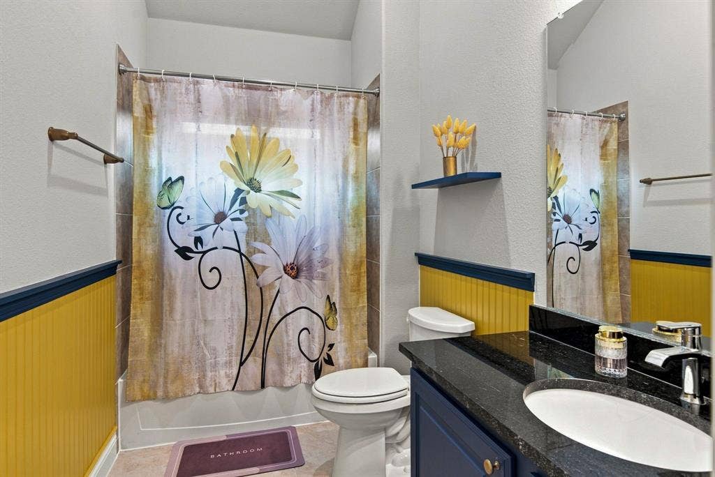 944 Tara Court, Haslet, TX 76052 Bathroom featuring a shower-tub combination, a dark granite-style countertop, a white oval undermount sink, and a navy blue vanity cabinet