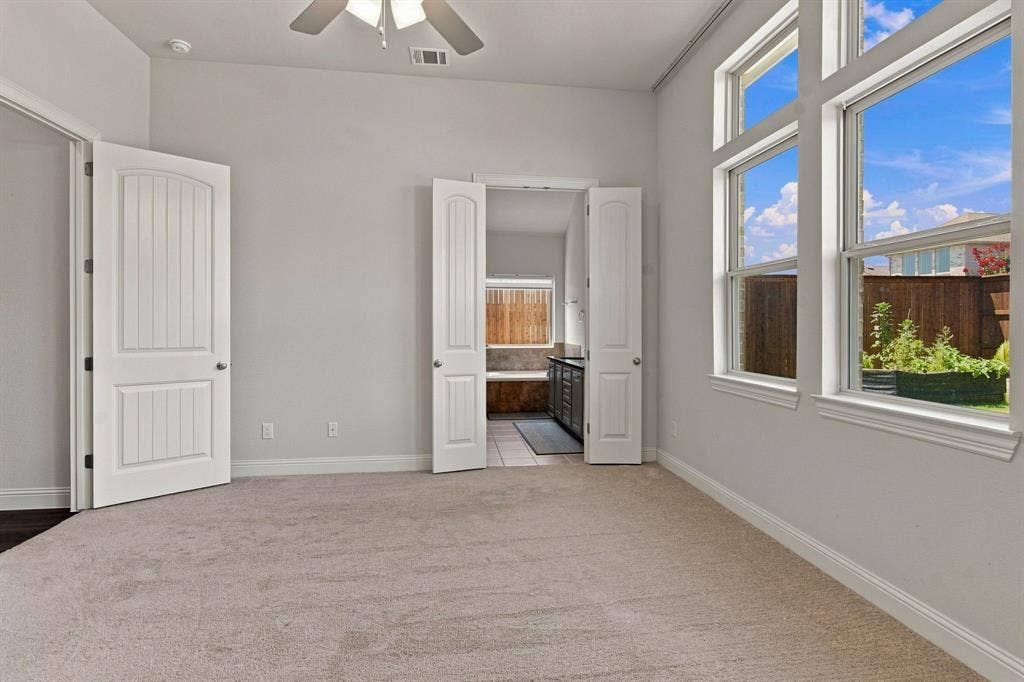 944 Tara Court, Haslet, TX 76052 Carpeted room featuring large windows, vaulted ceiling, and an integrated ceiling fan