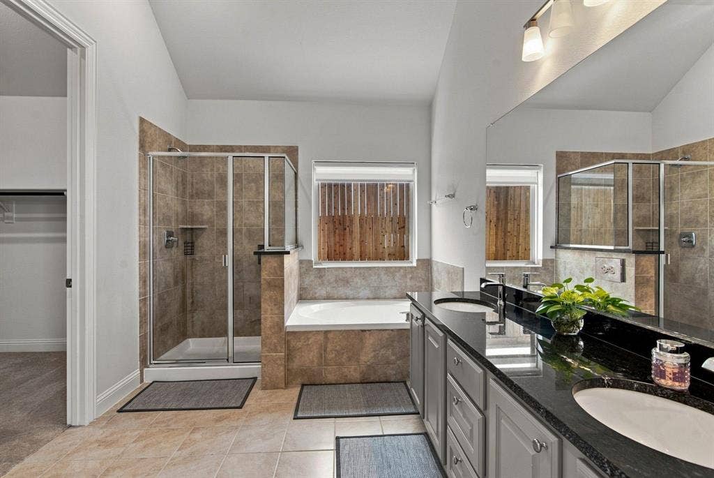 944 Tara Court, Haslet, TX 76052 Bathroom featuring a dual vanity with granite countertops, a built-in tub, and a separate glass-enclosed shower