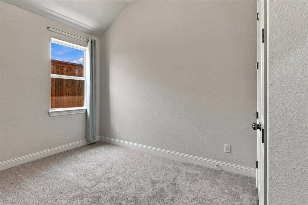 944 Tara Court, Haslet, TX 76052 Carpeted room featuring a single window with white trim, a wood fence visible outside, and a white door with dark hardware