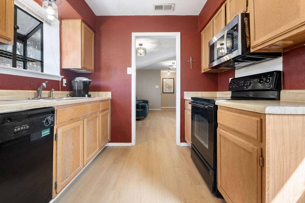 Galley kitchen with light wood-finish cabinetry, light wood-finish flooring, and light countertops