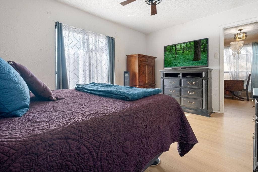 Light-toned wood-finish flooring extends throughout this room, featuring a window with sheer and blackout curtains