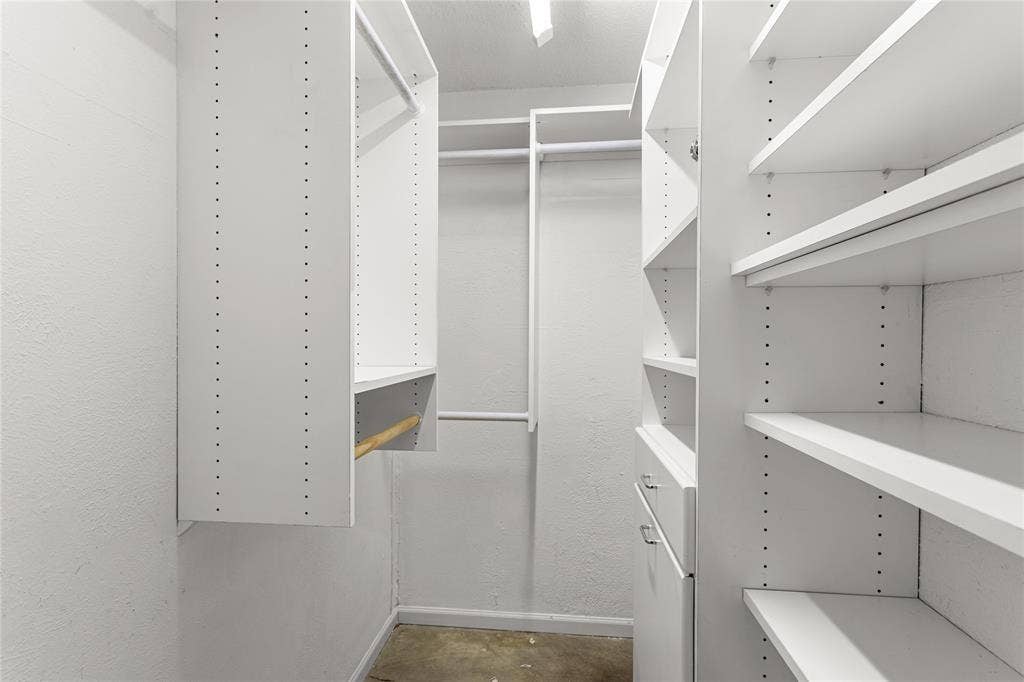 5916 Birchbrook Drive, #129, Dallas, TX 75206 Walk-in closet featuring white built-in shelving, multiple hanging rods, and adjustable shelf heights