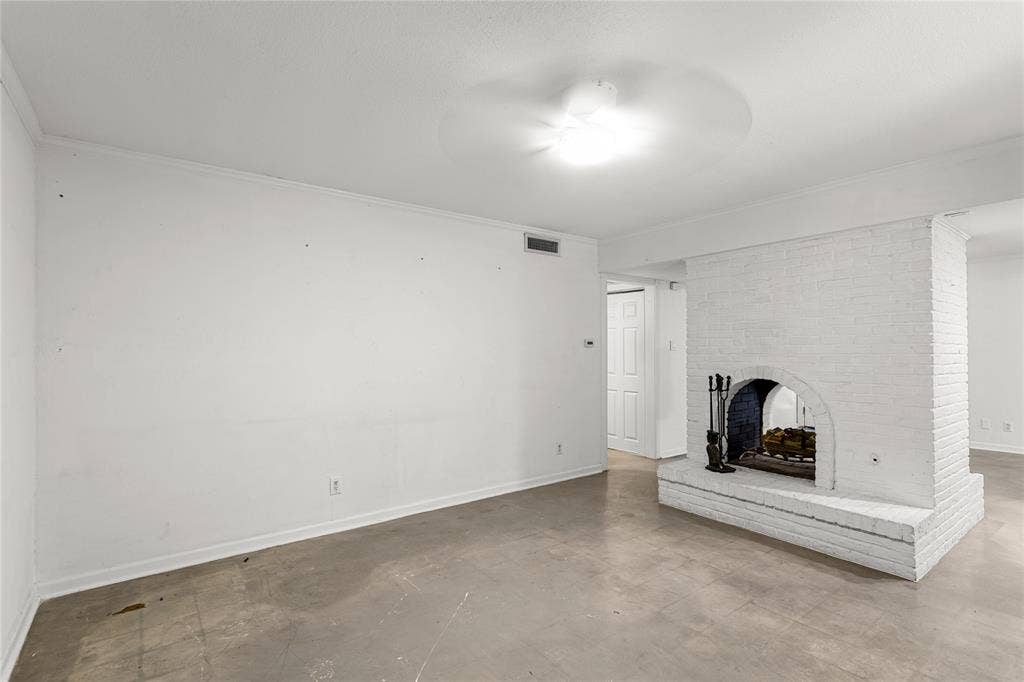 5916 Birchbrook Drive, #129, Dallas, TX 75206 Spacious room featuring a white-painted brick fireplace with a hearth, light-colored flooring, white walls, white baseboards, and a ceiling-mounted light fixture with a fan