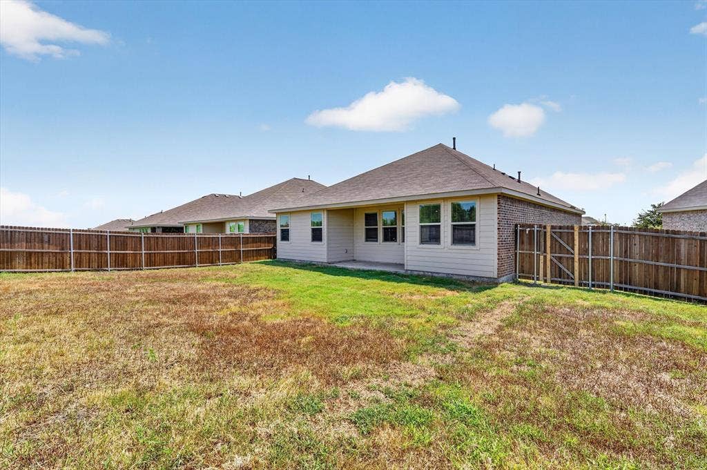 Spacious single-story home with a generous backyard featuring a manicured lawn and wooden privacy fencing