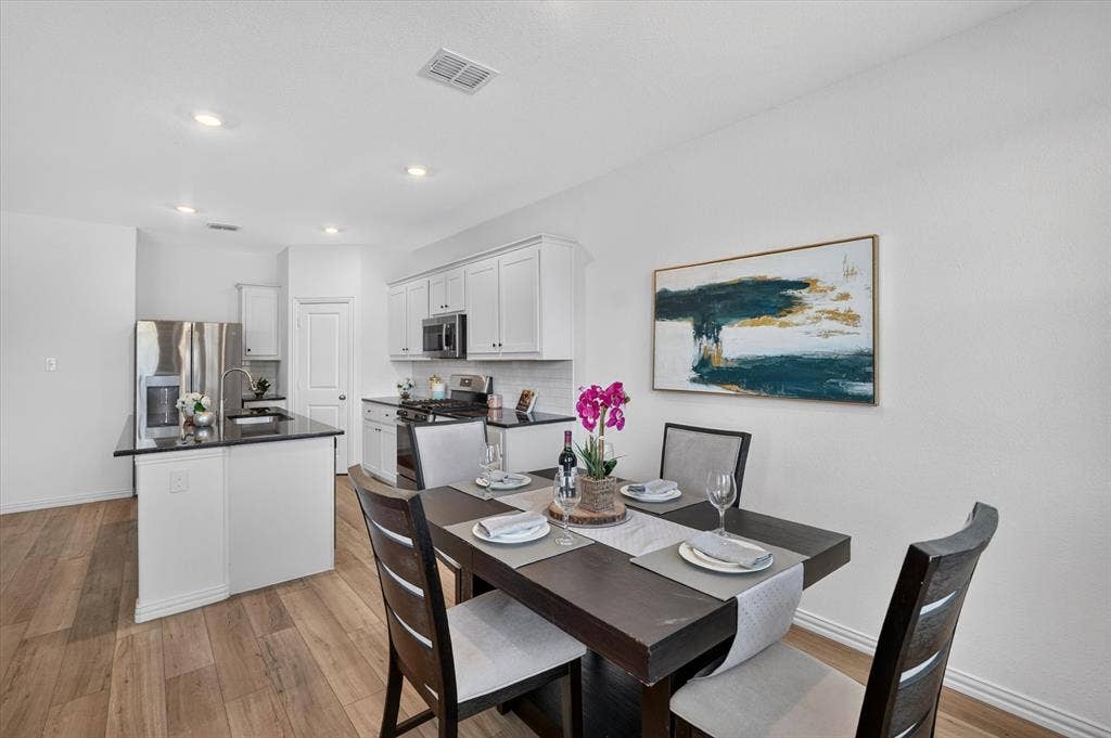 Open-concept living space featuring wood-finish flooring, recessed lighting, and a kitchen island with dark countertops