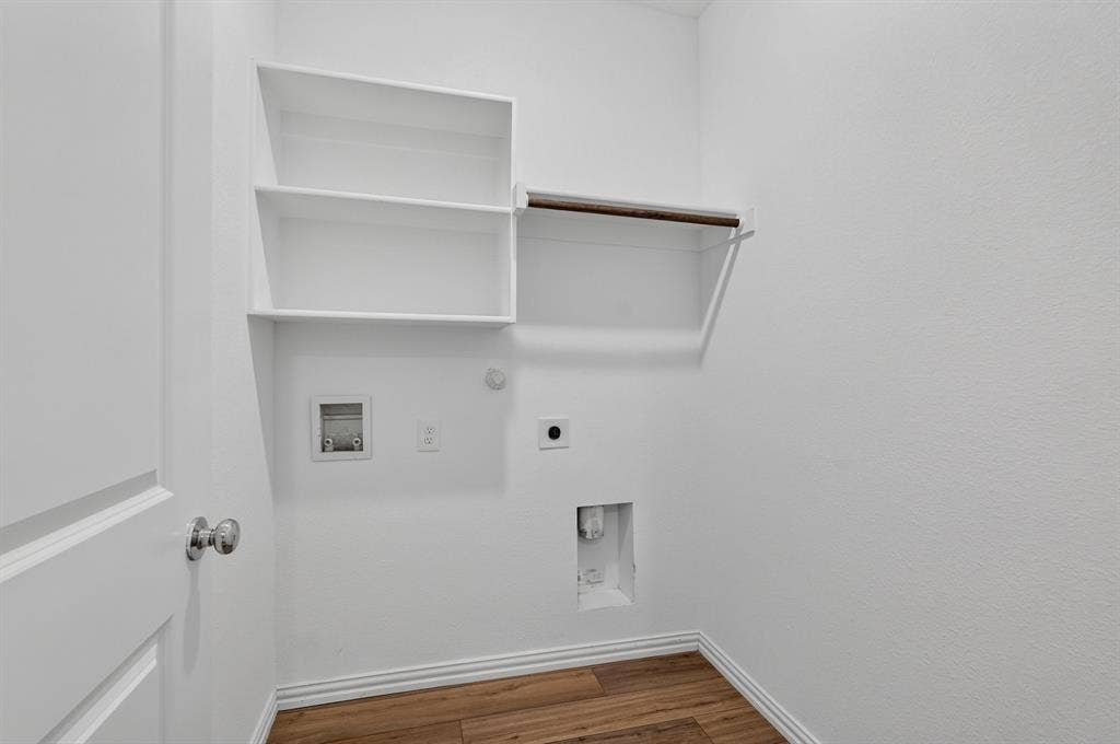 Utility area with white walls, wood-finish flooring, and white baseboards
