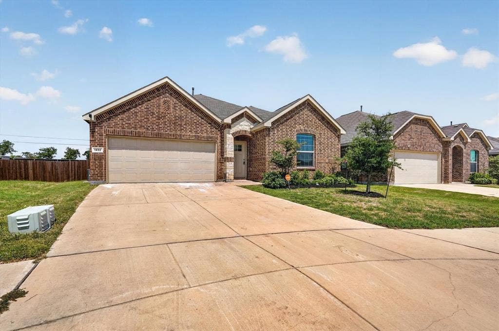 Welcoming brick exterior with a spacious two-car garage and expansive concrete driveway