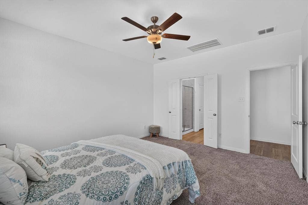 Carpeted bedroom with a ceiling fan