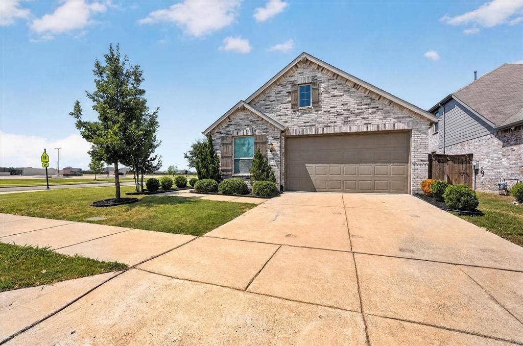 2832 Lolita Way, Forney, TX 75126 Brick facade home with an attached garage, landscaped front yard, and a concrete driveway