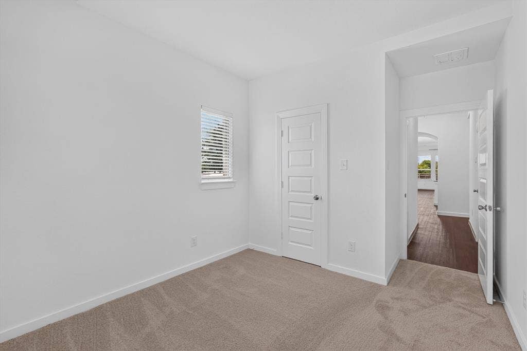 2832 Lolita Way, Forney, TX 75126 Bright bedroom featuring neutral carpeting, white six-panel interior doors, and a small fixed window with plantation shutters
