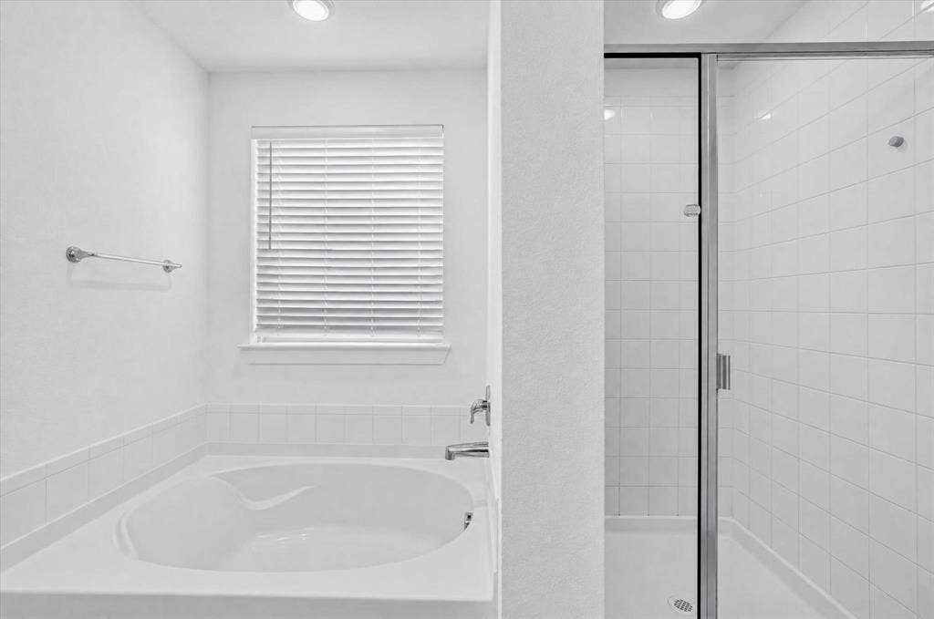 2832 Lolita Way, Forney, TX 75126 Spa-inspired primary bathroom featuring a deep soaking tub with integrated armrests, white subway tile surround, recessed ceiling lighting, and a frameless glass-enclosed shower stall with chrome hardware