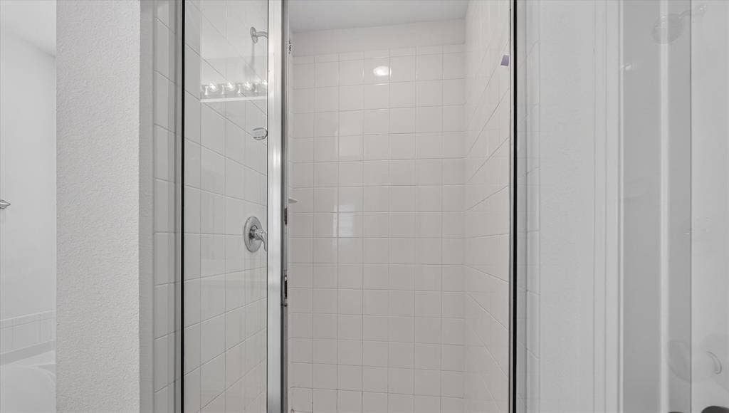 2832 Lolita Way, Forney, TX 75126 Spa-inspired shower enclosure featuring frameless glass doors, polished chrome hardware, and crisp white subway tile walls with integrated shelving for bath essentials