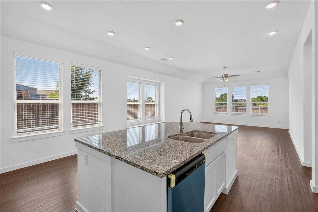 2832 Lolita Way, Forney, TX 75126 Chef's kitchen featuring a large center island with granite countertop, stainless steel sink with gooseneck faucet, white cabinetry, and dark blue island base