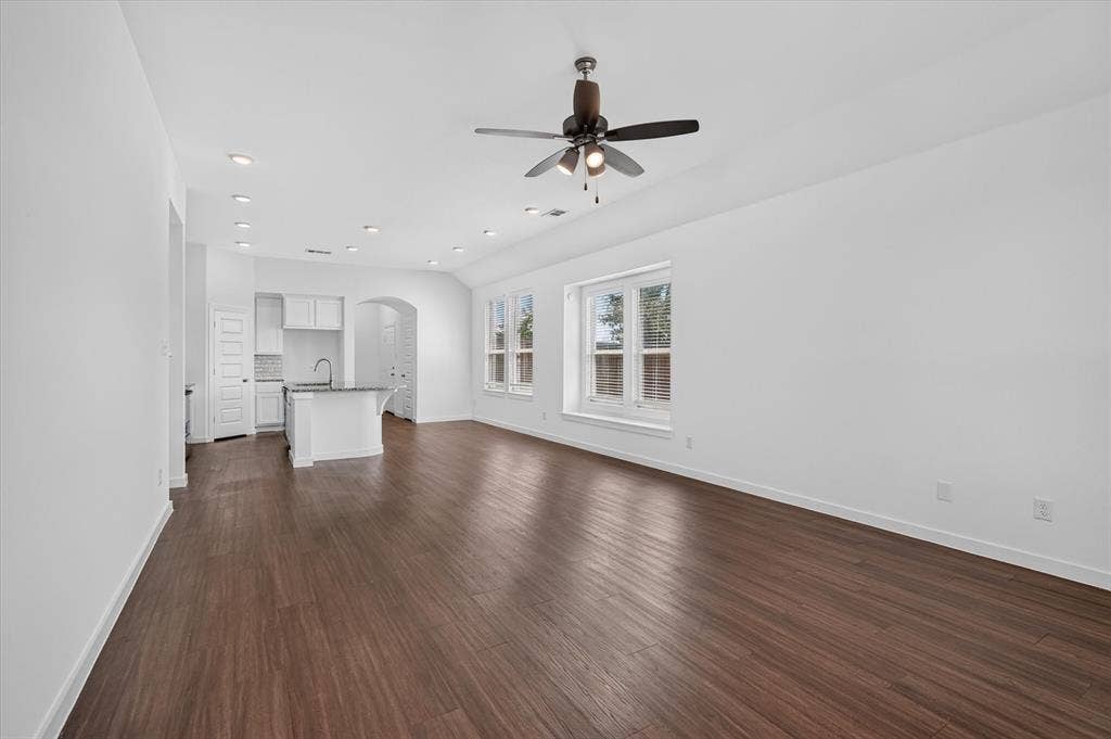 2832 Lolita Way, Forney, TX 75126 Spacious open-concept living area featuring rich wood-finish flooring throughout, white walls, and abundant natural light from multiple glass doors and windows