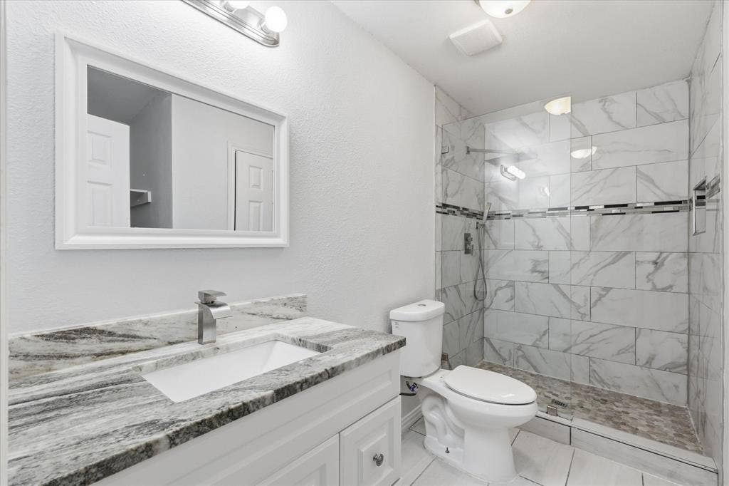 311 Bridlegate Drive, McKinney, TX 75069 Remodeled en-suite primary bath featuring an oversized shower with frameless glass and a granite vanity with a square sink.