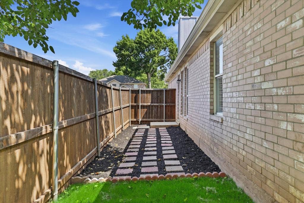 311 Bridlegate Drive, McKinney, TX 75069 Back view showing a manicured path leading into a spacious, grassy, non-HOA backyard.