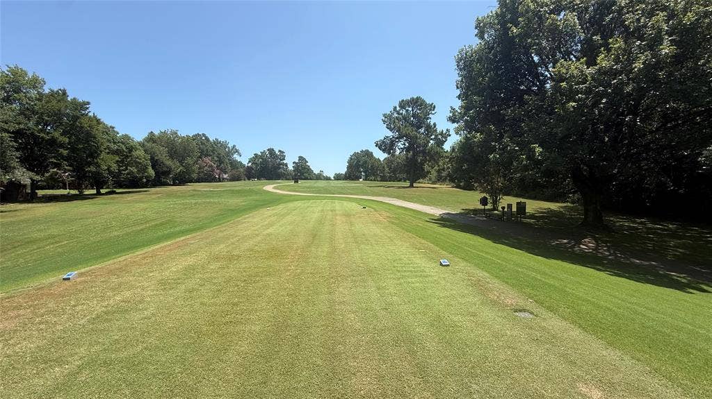106 E Fairway Drive, Hideaway, TX 75771 Expansive green space featuring a manicured lawn, established trees, and a visible golf course path