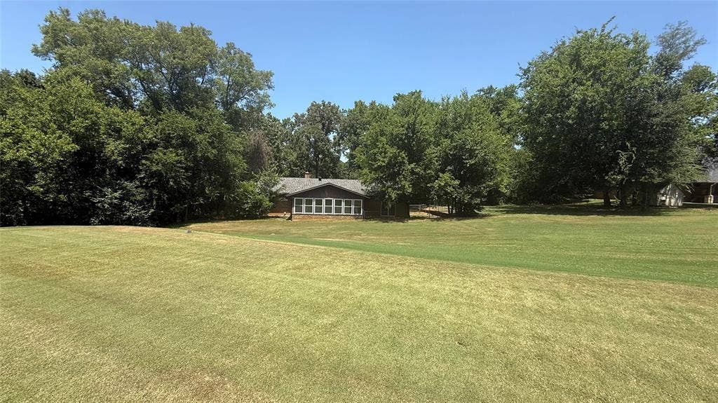 106 E Fairway Drive, Hideaway, TX 75771 Expansive green lawn bordering a single-story residence with a gabled roof and a wall of windows