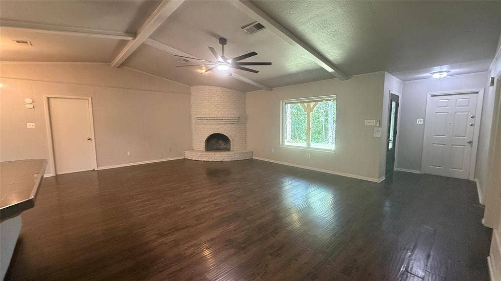 106 E Fairway Drive, Hideaway, TX 75771 Spacious living area featuring wood-finish flooring, an exposed beam ceiling, and a corner brick fireplace