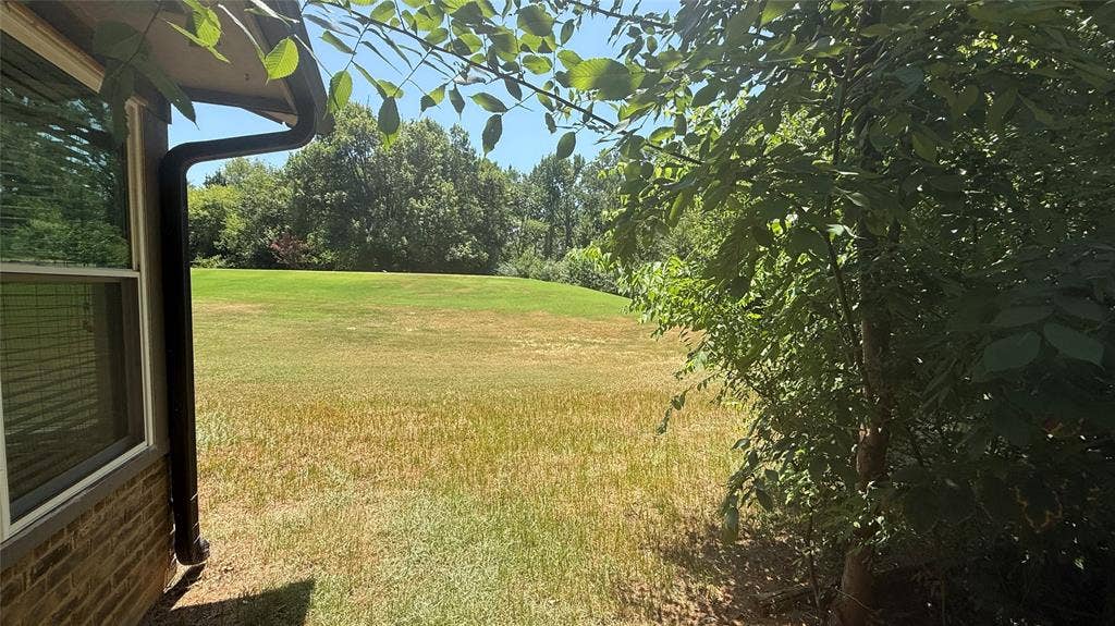 106 E Fairway Drive, Hideaway, TX 75771 Expansive rear yard featuring a large grassy area bordered by mature trees