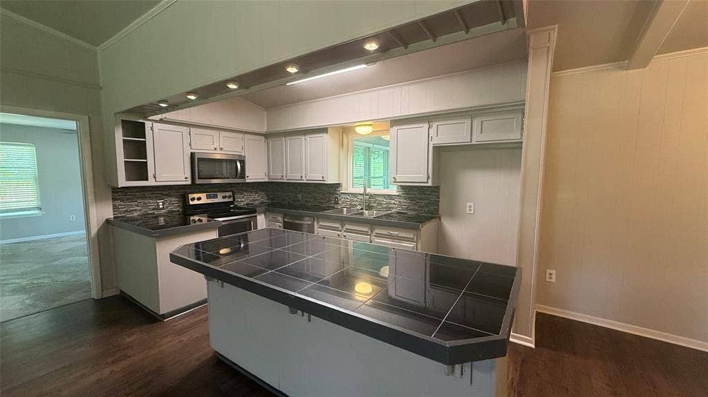106 E Fairway Drive, Hideaway, TX 75771 Kitchen featuring light-toned cabinetry, stainless steel appliances, dark countertops, and a tile backsplash