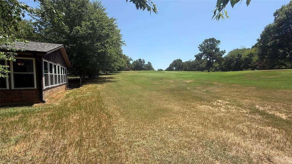 106 E Fairway Drive, Hideaway, TX 75771 Expansive lawn area with mature trees bordering a golf course