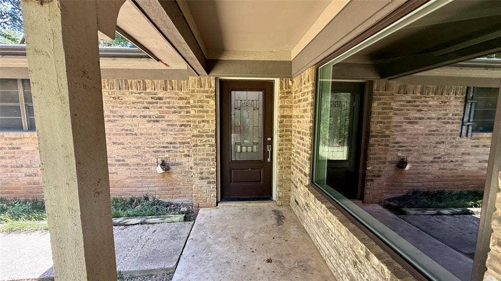 106 E Fairway Drive, Hideaway, TX 75771 Brick exterior with a covered entry, featuring a decorative glass panel front door and a prominent fixed window