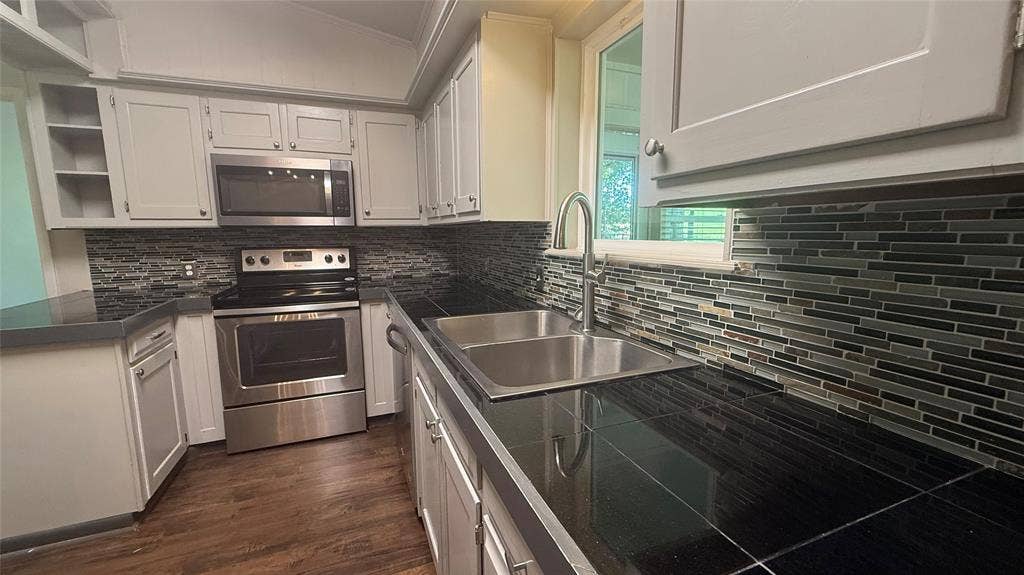 106 E Fairway Drive, Hideaway, TX 75771 Kitchen featuring wood-finish flooring and light-toned cabinetry