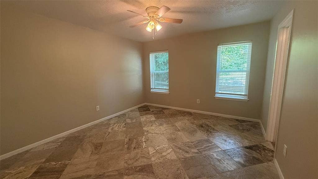 106 E Fairway Drive, Hideaway, TX 75771 Spacious room featuring multi-tone tile flooring, neutral wall paint, and two windows with blinds