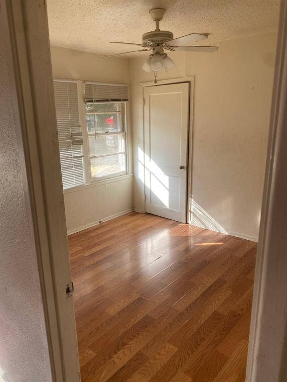 Wood-finish flooring, ceiling fan with integrated lighting, and multiple windows