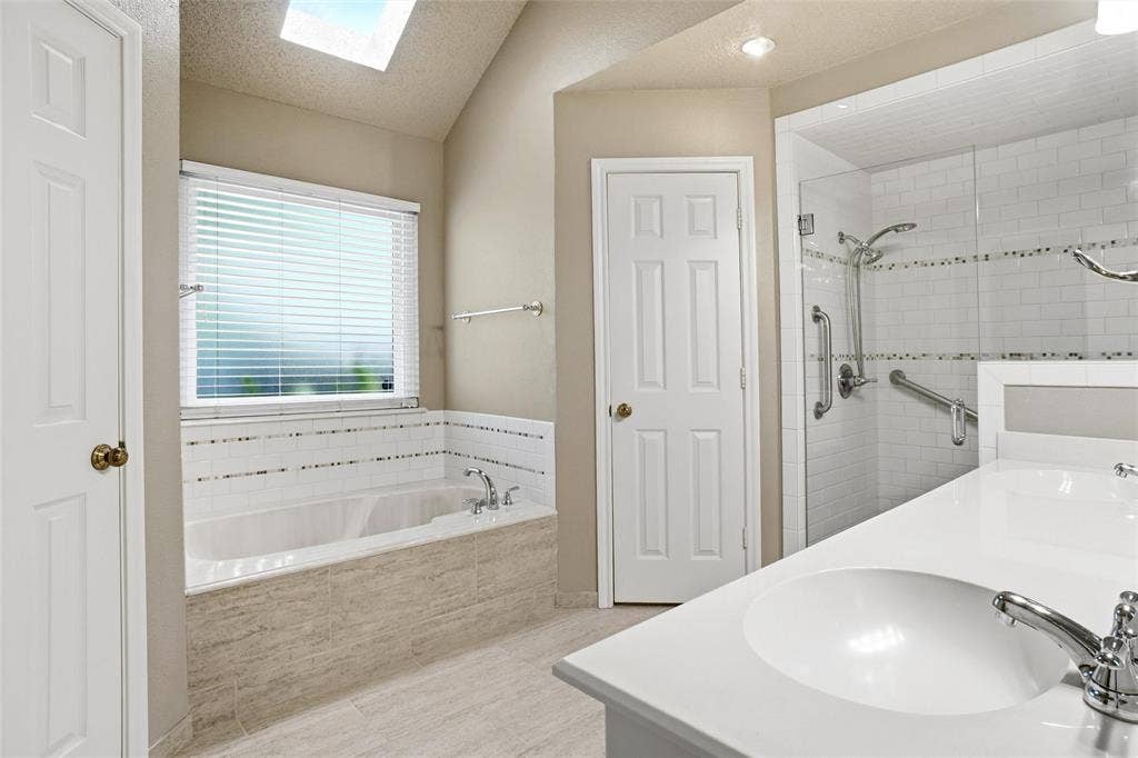 1321 Oak Harbor Boulevard, Azle, TX 76020 Primary Bath features separate vanities, a garden tub, a spacious walk-in shower, and dual walk-in closets.