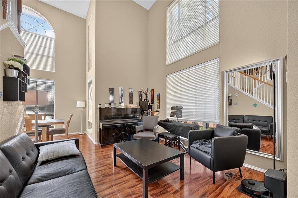 1625 Falmouth Drive, Plano, TX 75025 Vaulted ceilings with multiple windows, including an arched transom window, define this open living area featuring wood-finish flooring and neutral-toned walls