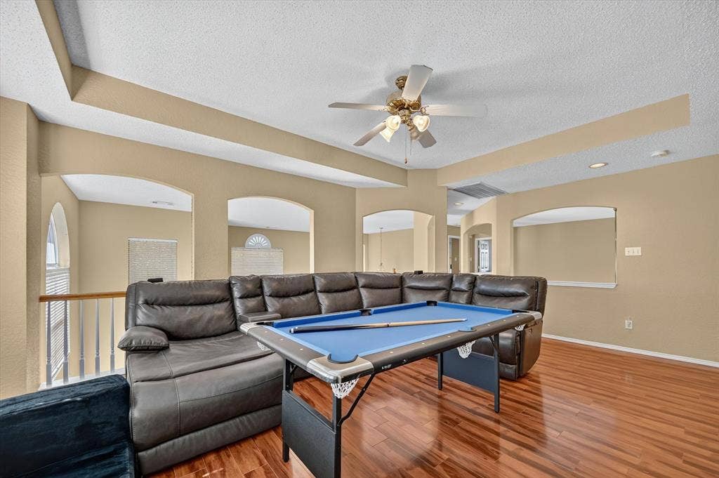 1625 Falmouth Drive, Plano, TX 75025 Upper-level room featuring wood-finish flooring, a ceiling fan, and arched wall openings overlooking a lower level