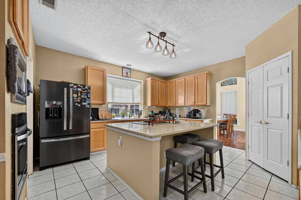 1625 Falmouth Drive, Plano, TX 75025 Kitchen featuring an island with countertop seating, light wood-finish cabinetry, a built-in oven, and a double-door pantry