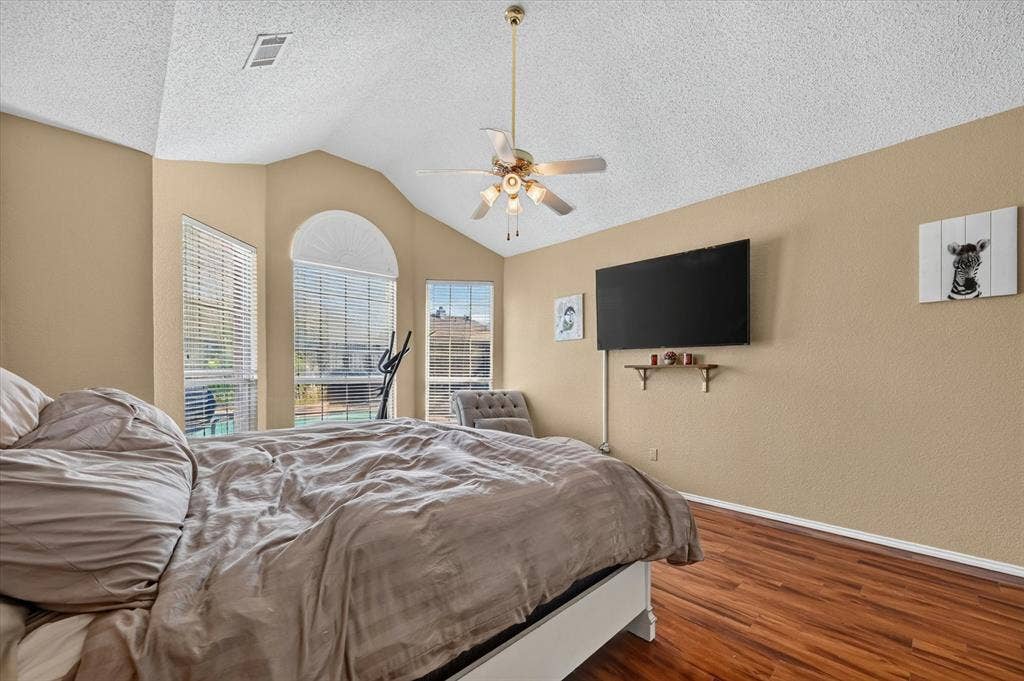 1625 Falmouth Drive, Plano, TX 75025 Vaulted ceiling interior featuring multiple windows with blinds, a ceiling fan, and wood-finish flooring