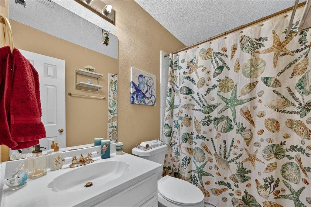 1625 Falmouth Drive, Plano, TX 75025 Full bathroom featuring a white vanity with an integrated sink, a large wall-mounted mirror, a two-bulb vanity light fixture, and a toilet